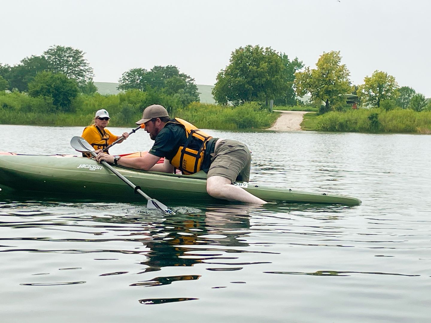 A bearded man works to pull himself up the rear of kayaking while doing a wet exit and self-rescue called "cowboy."