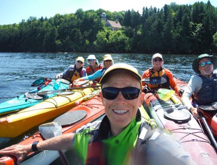 A group of people in kayaks gather together for a smiling group picture. 