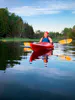 Middle-aged woman sits in a Red Sea kayak with her eyes closed soaking up the peace and tranquility of nature while on a kayak tour.