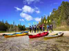 A group of female sea kayaks stands on a shoreline with their paddles taking a break on a guided kayak tour in Lake Huron.