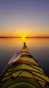 A yellow kayak faces the sunset on Lake Huron in the Les Cheneaux Island with calm waters all around.