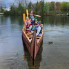 Group of people in an extremely large canoe having fun.